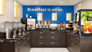 A breakfast buffet area with a blue wall and various food dispensers. - Days Inn by Wyndham Wainwright (Wainwright)