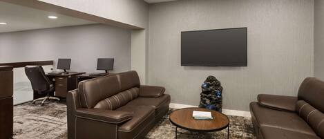 A modern lounge with leather sofas, a flat-screen TV, and a small table.