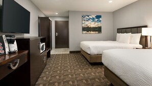 A hotel room with a bed, a TV, a coffee maker, and a painting on the wall. - Days Inn by Wyndham Wainwright (Wainwright)