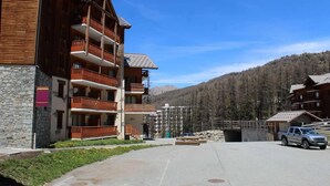 Un edificio de madera de varios pisos, con balcones, fachada de piedra y montañas al fondo.