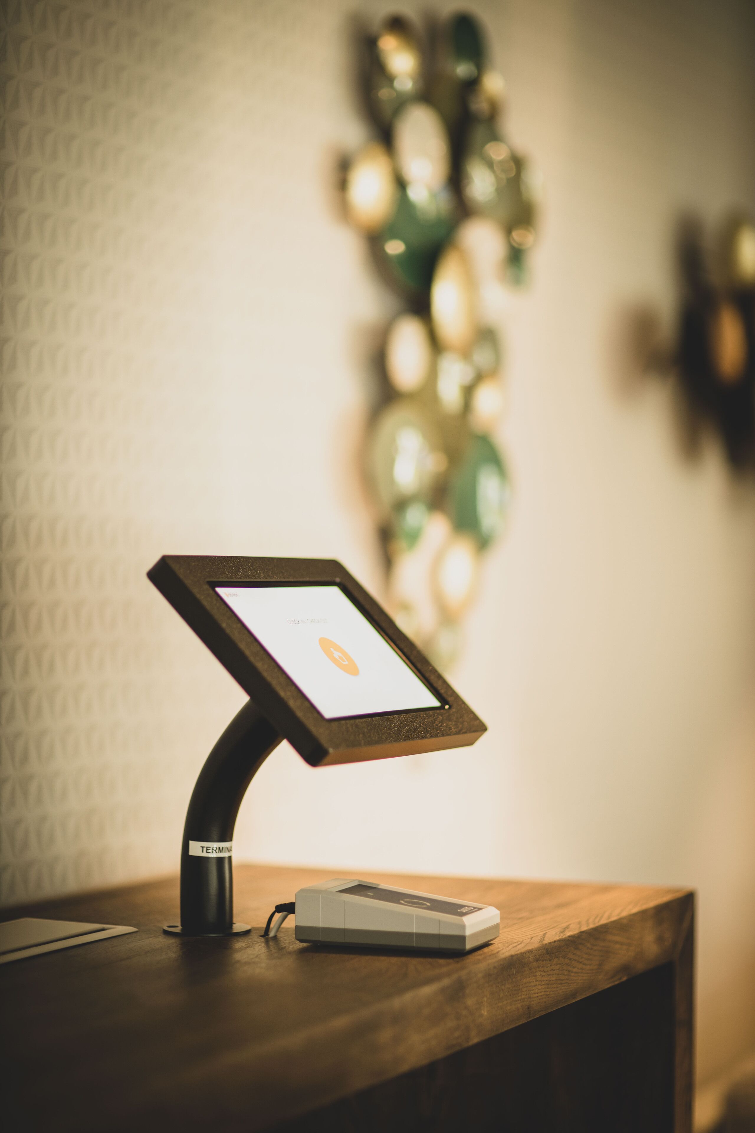 A digital kiosk with a screen displaying a map, a charging station, and a wooden counter.
