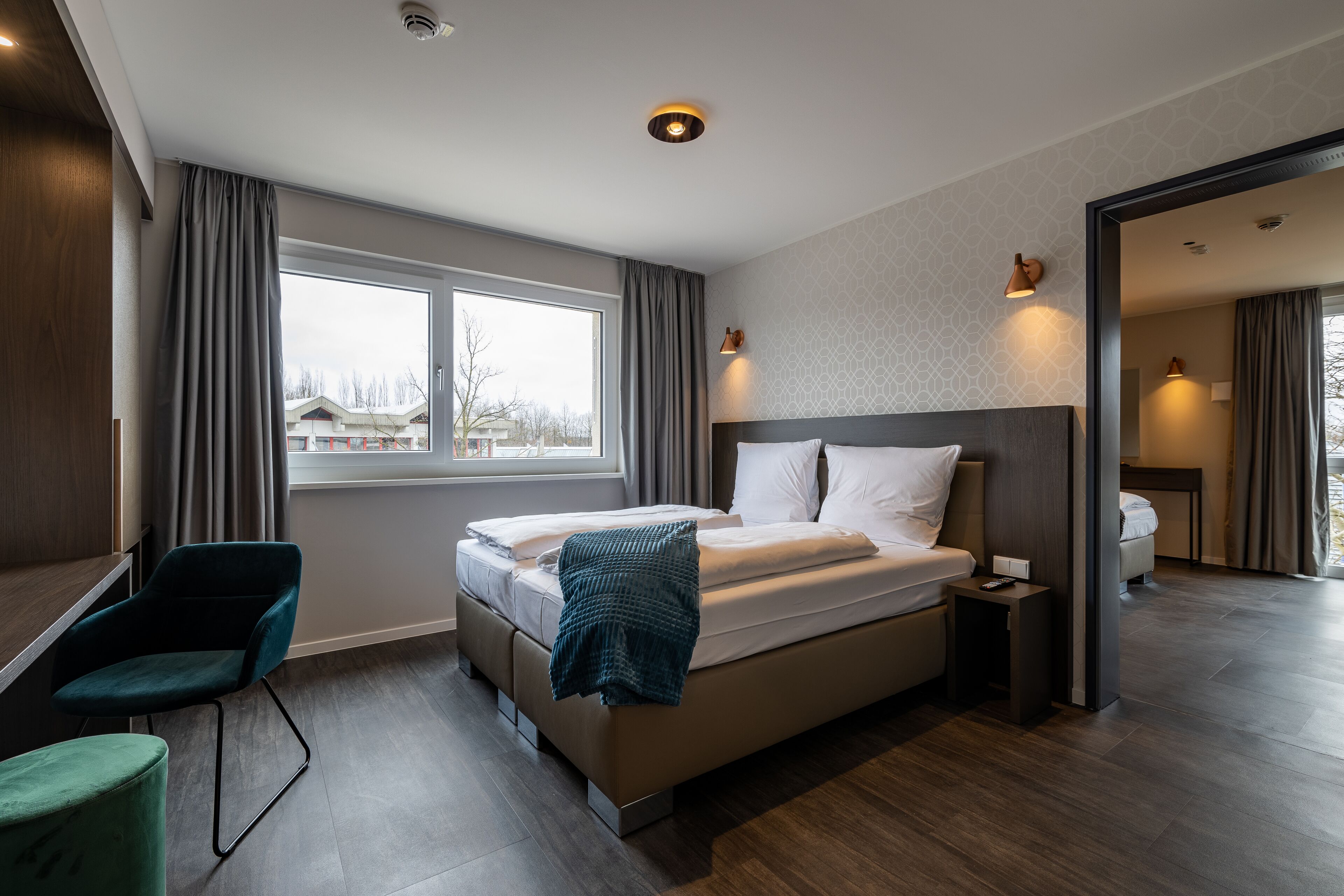 A modern hotel room with a large bed, a desk, and a chair.