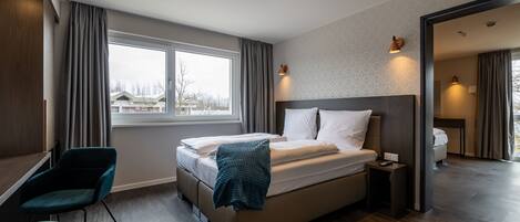 A modern hotel room with a large bed, a desk, and a chair.
