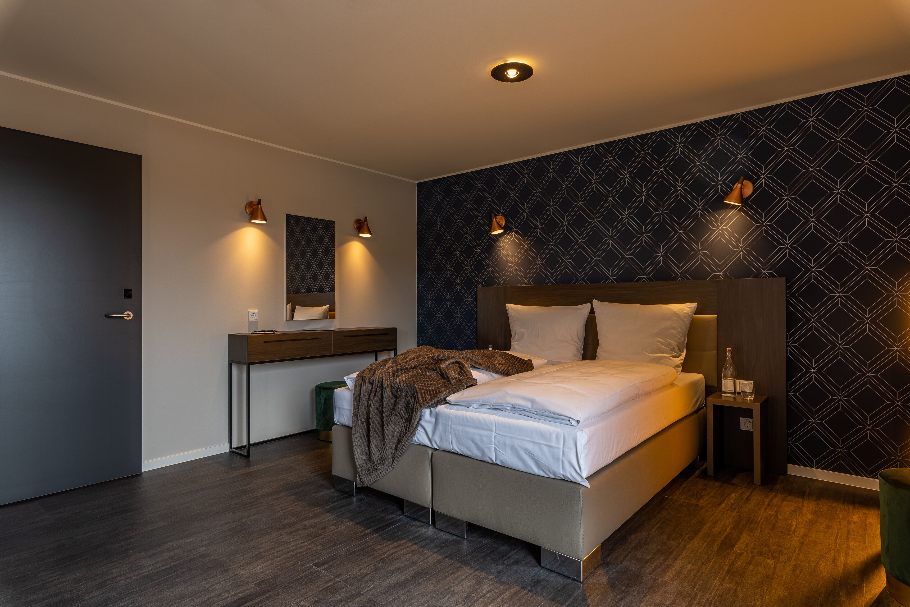 Een moderne slaapkamer met een bed, nachtkastjes, een dressoir en een behang met een patroon.