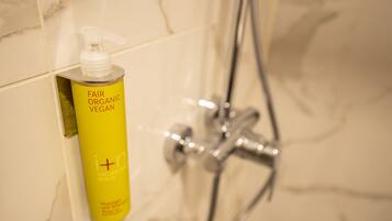 A yellow bottle of Fair Organic Vegan shampoo on a bathroom wall.