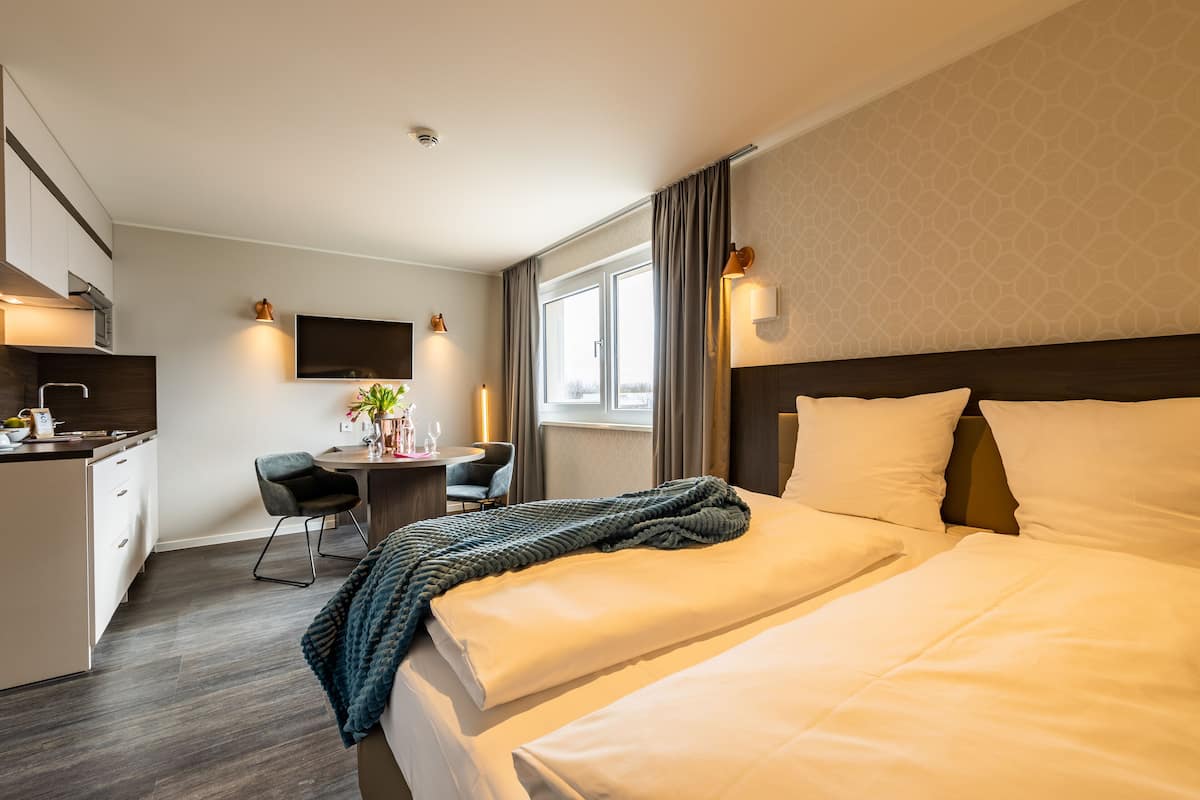 A hotel room with a bed, a desk, a chair, and a TV.