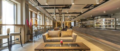 A modern interior with a seating area, a bar, and a kitchen visible.