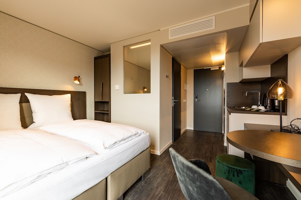 A modern hotel room with a large bed, a small desk, and a mirror.