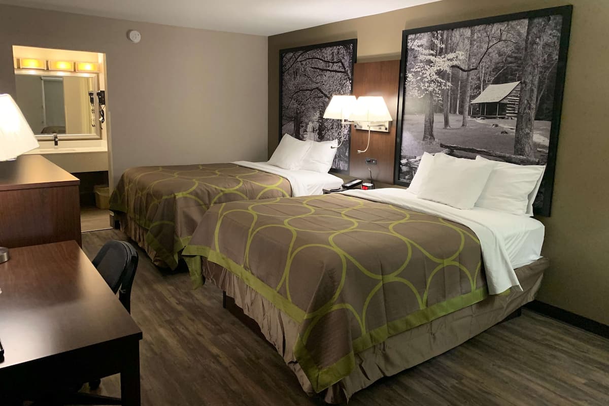 Une chambre d’hôtel avec deux lits, un bureau, une chaise, un miroir et un tableau au mur.