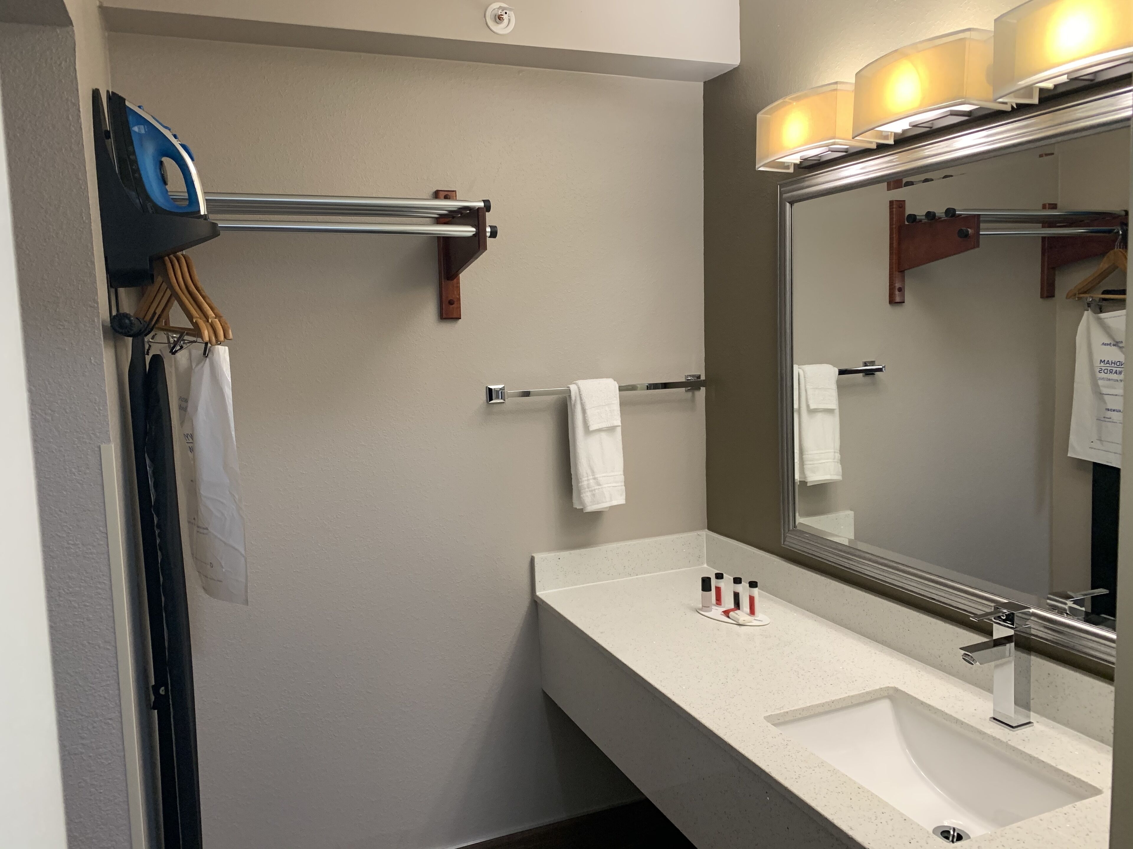 A bathroom with a white sink, a mirror, and a towel rack.