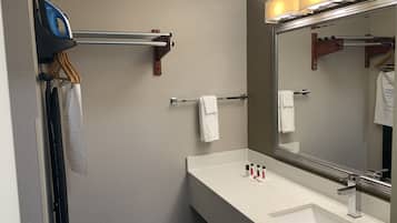 Een badkamer met een wit wastafel, een spiegel en een handdoekhouder.