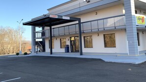 A modern building with a covered entrance, a sign indicating a 13ft clearance, and a visible entrance door. - Super 8 by Wyndham Cookeville (Cookeville)