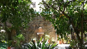 A courtyard with a stone wall, a fountain, and potted plants. - L'Aranceto Sorrentino Residence (Meta)