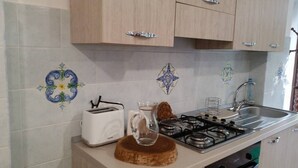 A kitchen with a toaster, a gas stove, and a sink. - L'Aranceto Sorrentino Residence (Meta)