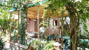 An outdoor patio area with a wooden pergola, a table with chairs, and various potted plants. - L'Aranceto Sorrentino Residence (Meta)