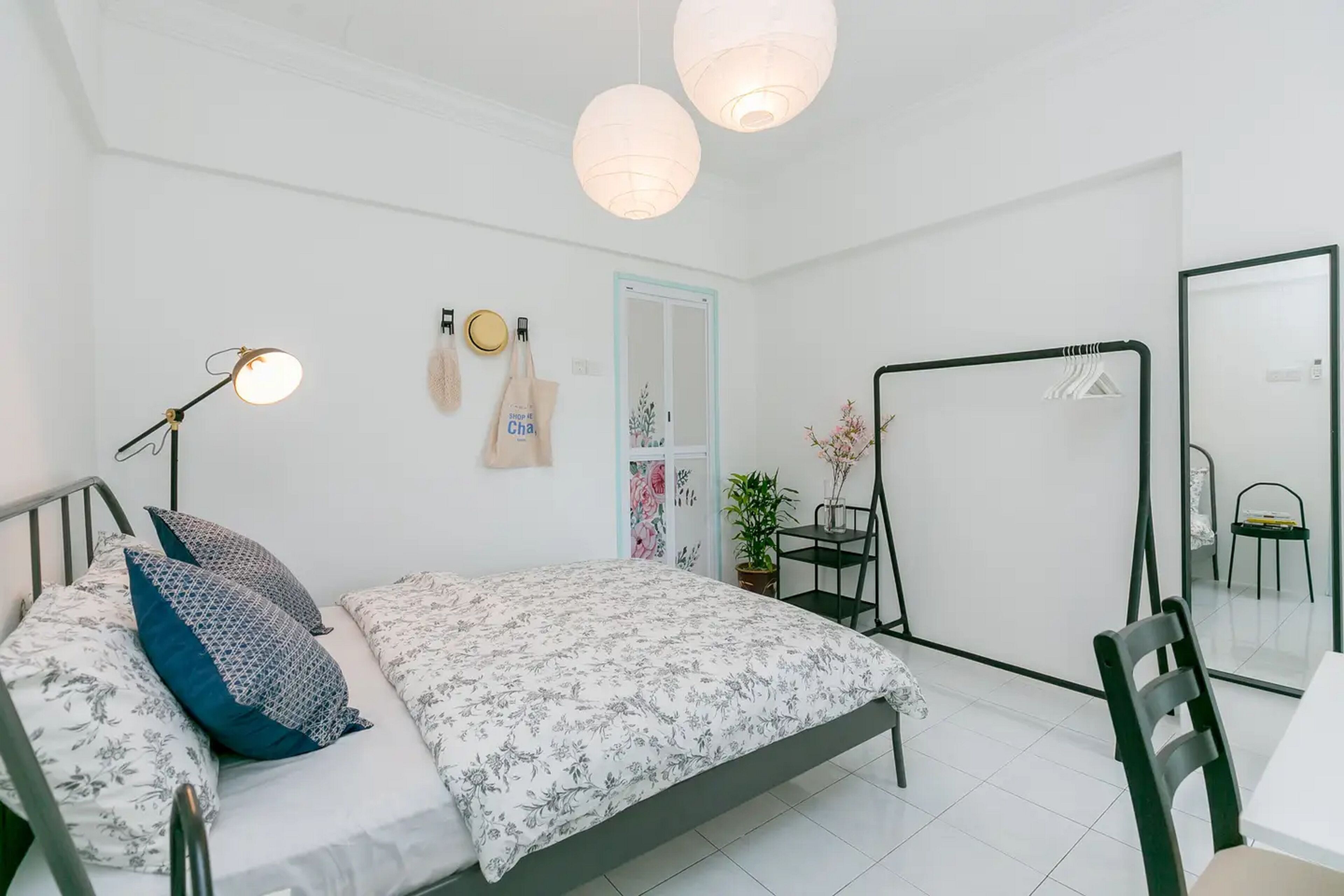 A bedroom with a bed, bedside lamp, wall-mounted towel, and a mirror.