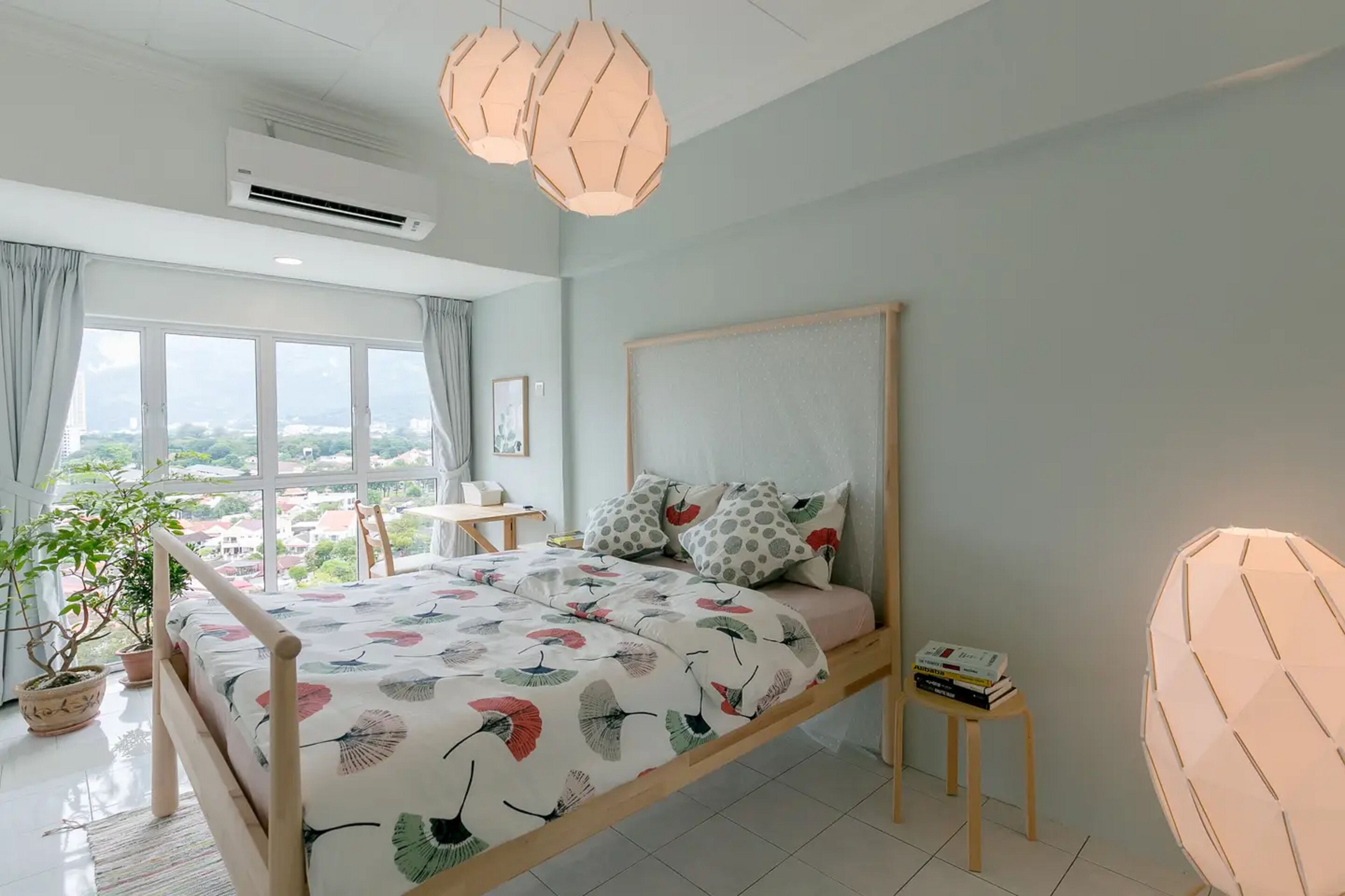 A bedroom with a bed, a desk, a chair, and a potted plant.