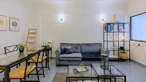 A modern living room with a glass dining table, grey sofa, and a black bookshelf. - Eastern Court 22 by Sanguine (George Town)