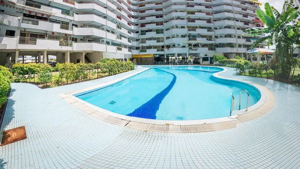 A modern multi-story hotel with a central swimming pool, surrounded by greenery and a covered walkway. - Eastern Court 22 by Sanguine (George Town)