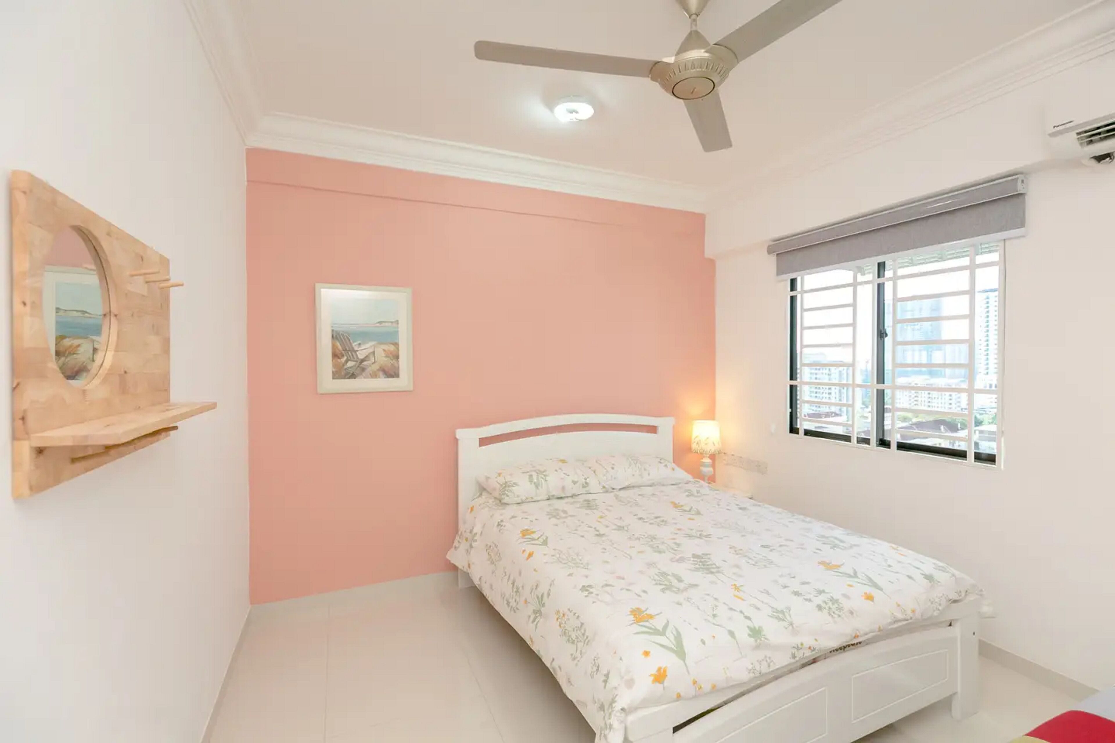A bedroom with a bed, a ceiling fan, a window with blinds, a wall-mounted shelf, and a framed picture.