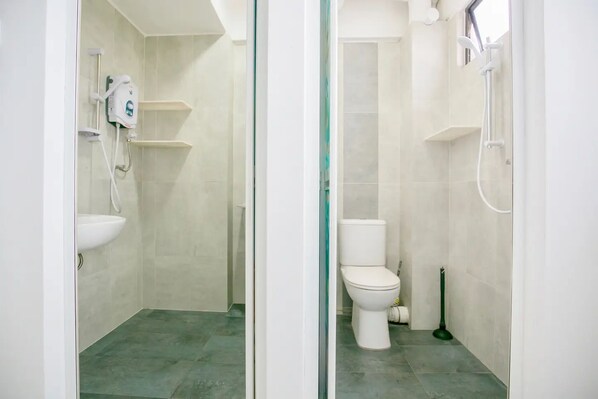 A bathroom with a toilet, a sink, a shower, and a handheld showerhead.
