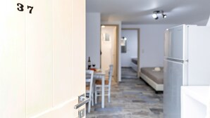 Un pasillo que conduce a un dormitorio con una cama, una mesita y una silla.