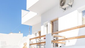 Un edificio blanco con una escalera de madera, un balcón y un equipo de aire acondicionado.