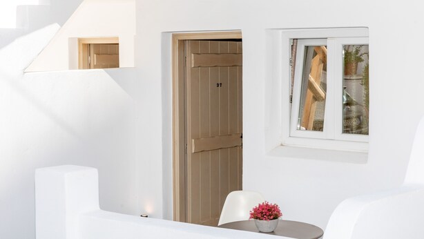 Una habitación moderna y minimalista, con pared blanca, puerta de madera y un ventanal pequeño.
