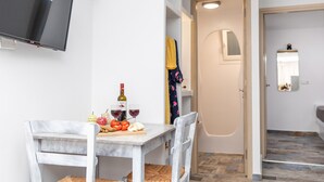 Un comedor con una mesa dispuesta para dos, una botella de vino y una bandeja de frutas.