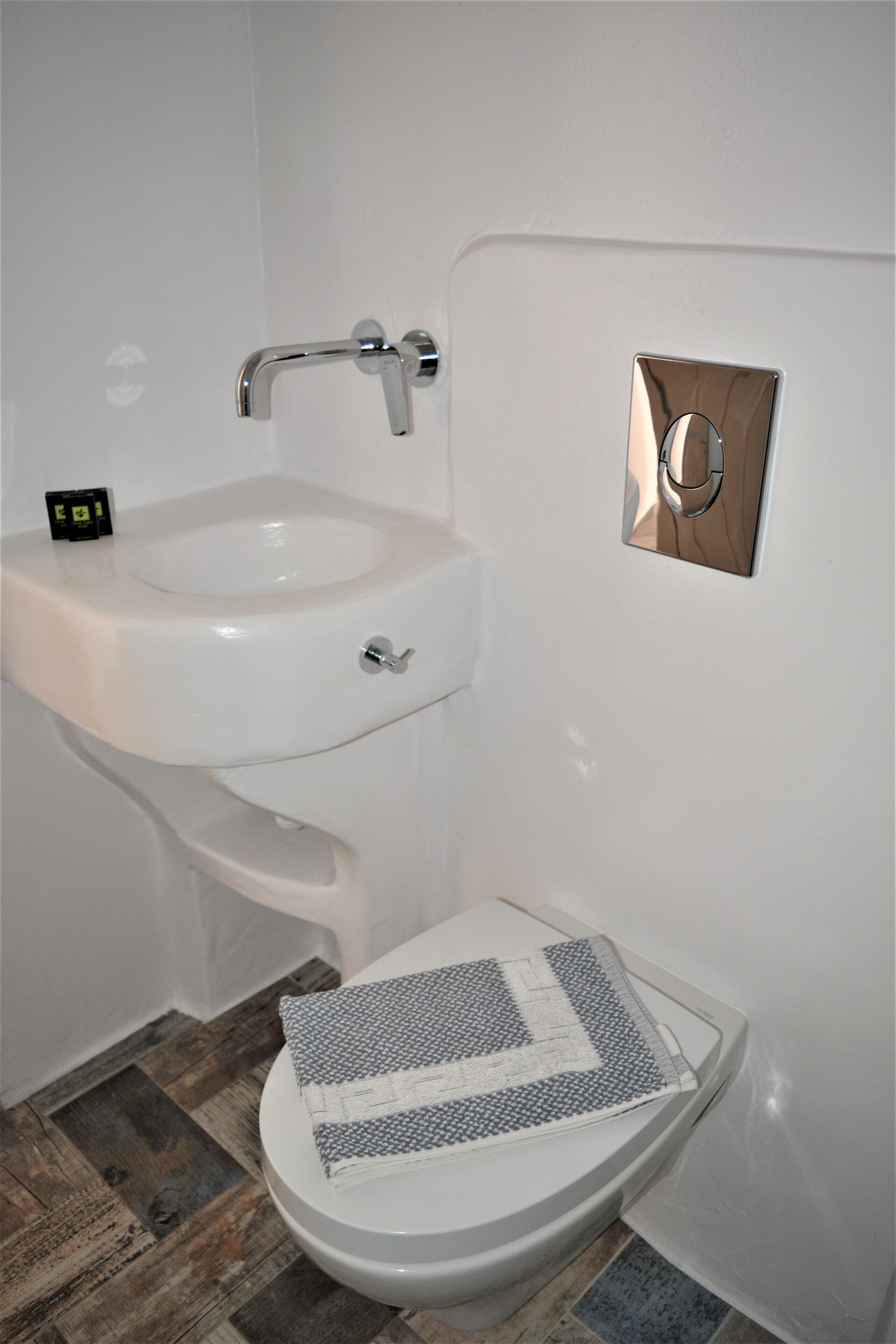 Ein Badezimmer mit Toilette, Waschbecken und Holzboden.