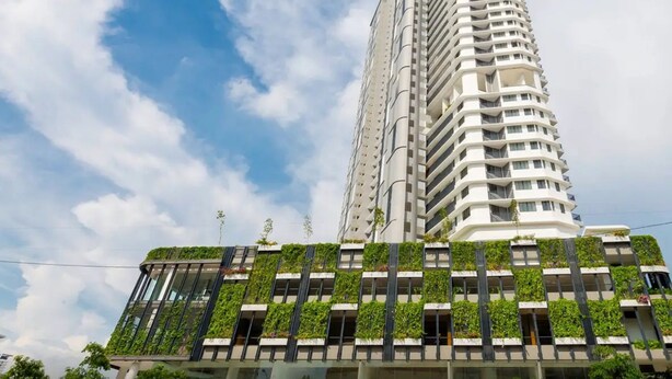 A tall, modern building with a unique architectural design, featuring a series of balconies and a rooftop garden.