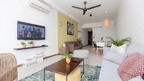 A modern living room with a sofa, a coffee table, a TV mounted on the wall, and a ceiling fan.