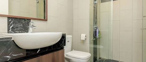 A modern bathroom with a large white sink, a toilet, and a glass-enclosed shower.