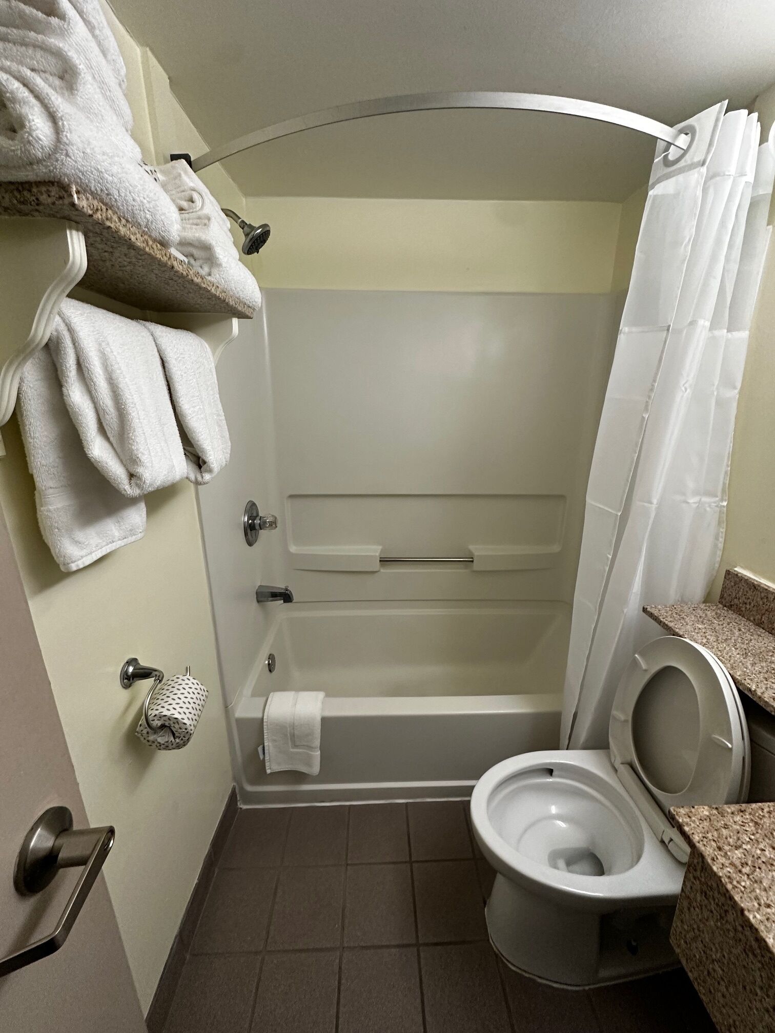 A small, compact bathroom with a shower, toilet, and towel rack.