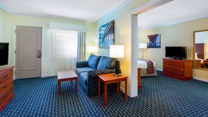 Habitación de hotel con sofá, dos lámparas, televisor, cómoda y espejo.