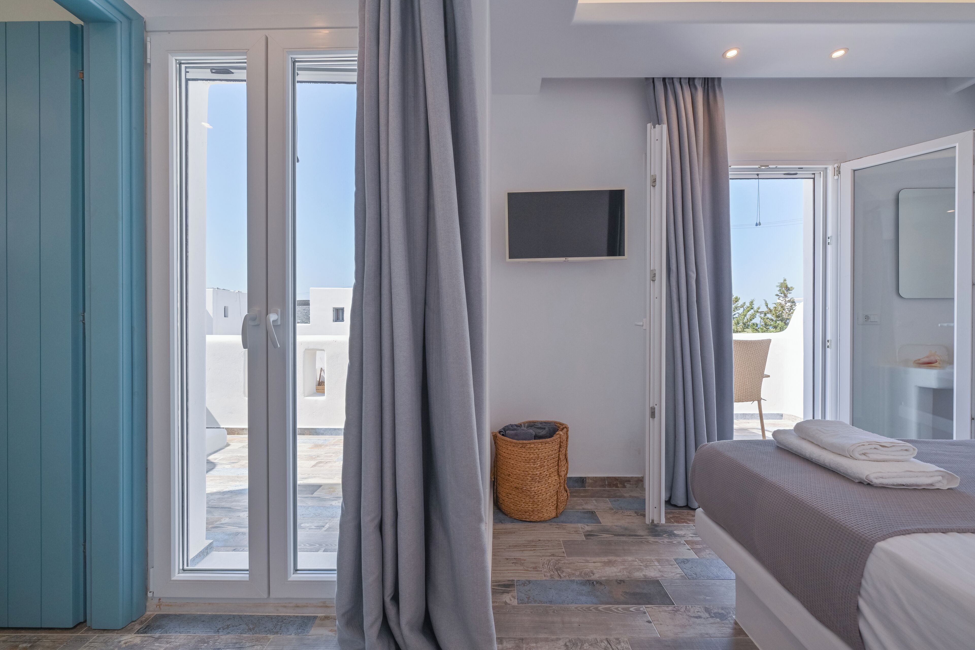 A modern bedroom with a bed, a TV, and a view of the outside.