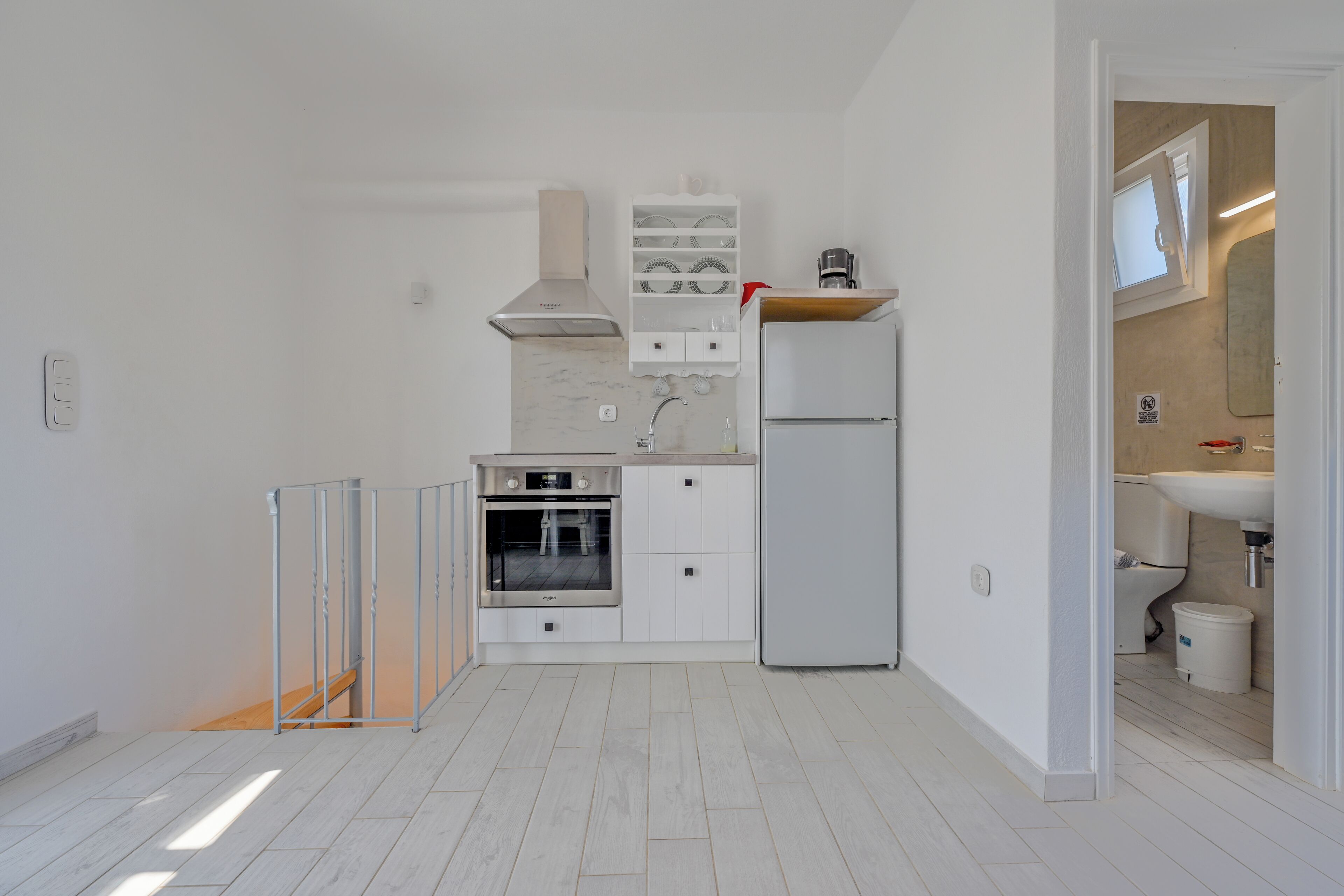 A modern kitchen with white cabinets, a stainless steel oven, a built-in microwave, and a refrigerator.