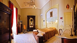 Una habitación de hotel clásica con una cama grande, un armario de madera, un escritorio con una silla y un espejo.