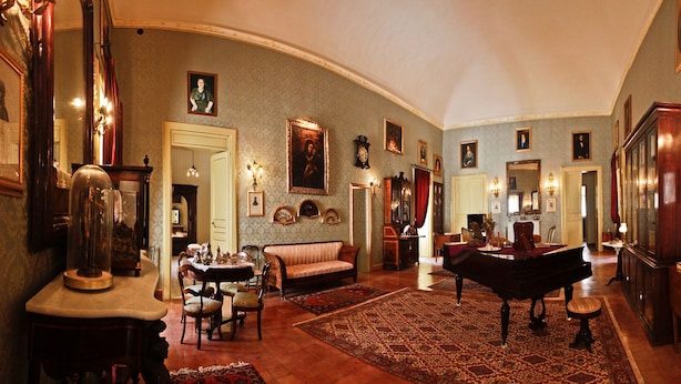 Una habitación amplia con un piano, un sofá, una mesa de comedor y un espejo grande.