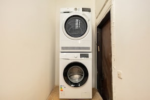 A stacked washer and dryer unit in a room with a wooden door and a white wall.