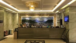 A hotel reception area with a large mural of a mountainous landscape, a reception desk, and a chandelier. - Vyluk J Hotel Fuxing Road Lijiang (Lijiang)