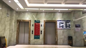 An elevator area with marble walls, two elevators, and a directory sign. - Vyluk J Hotel Fuxing Road Lijiang (Lijiang)