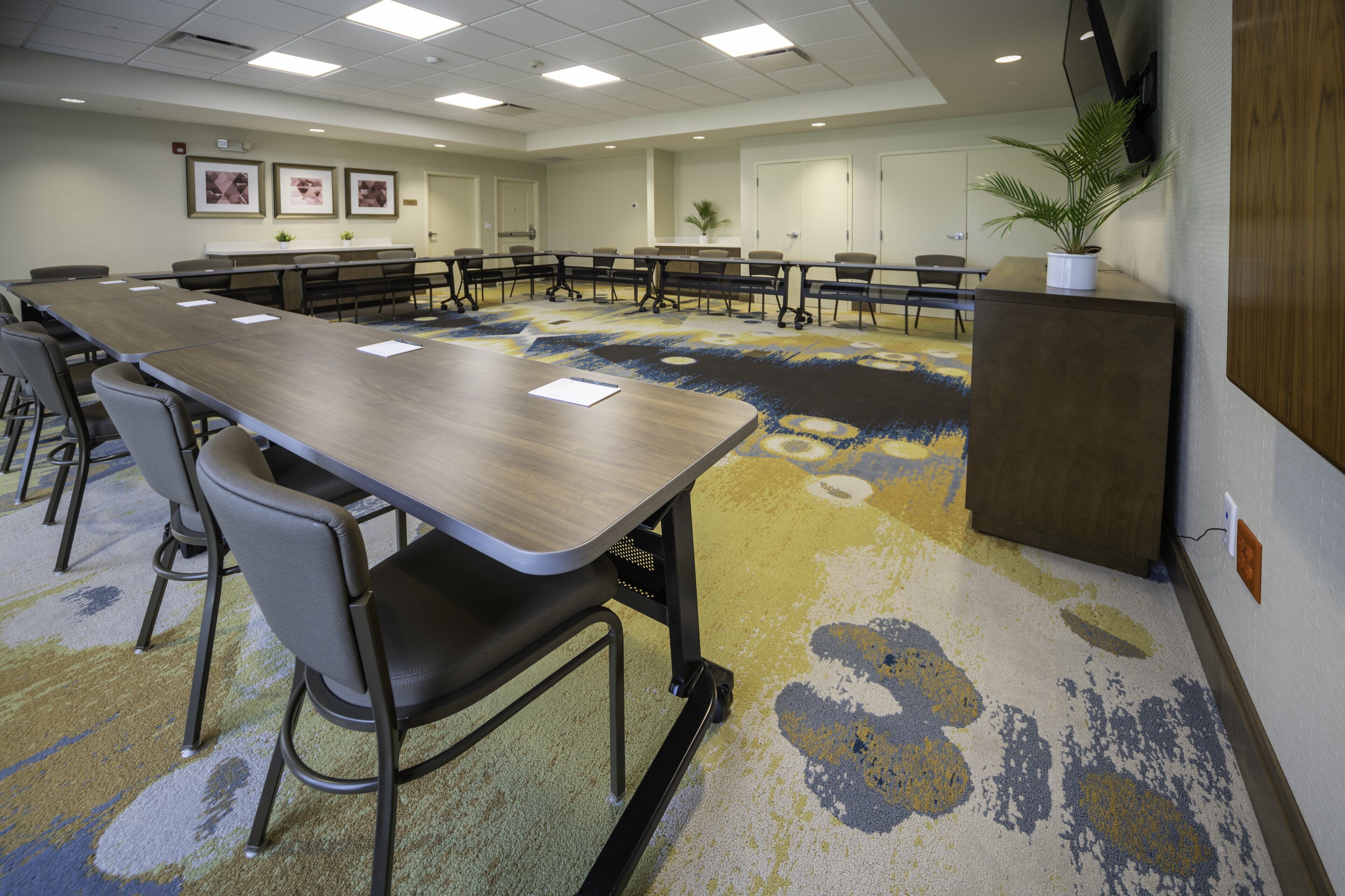 A conference room with a long table, chairs, and a carpeted floor.