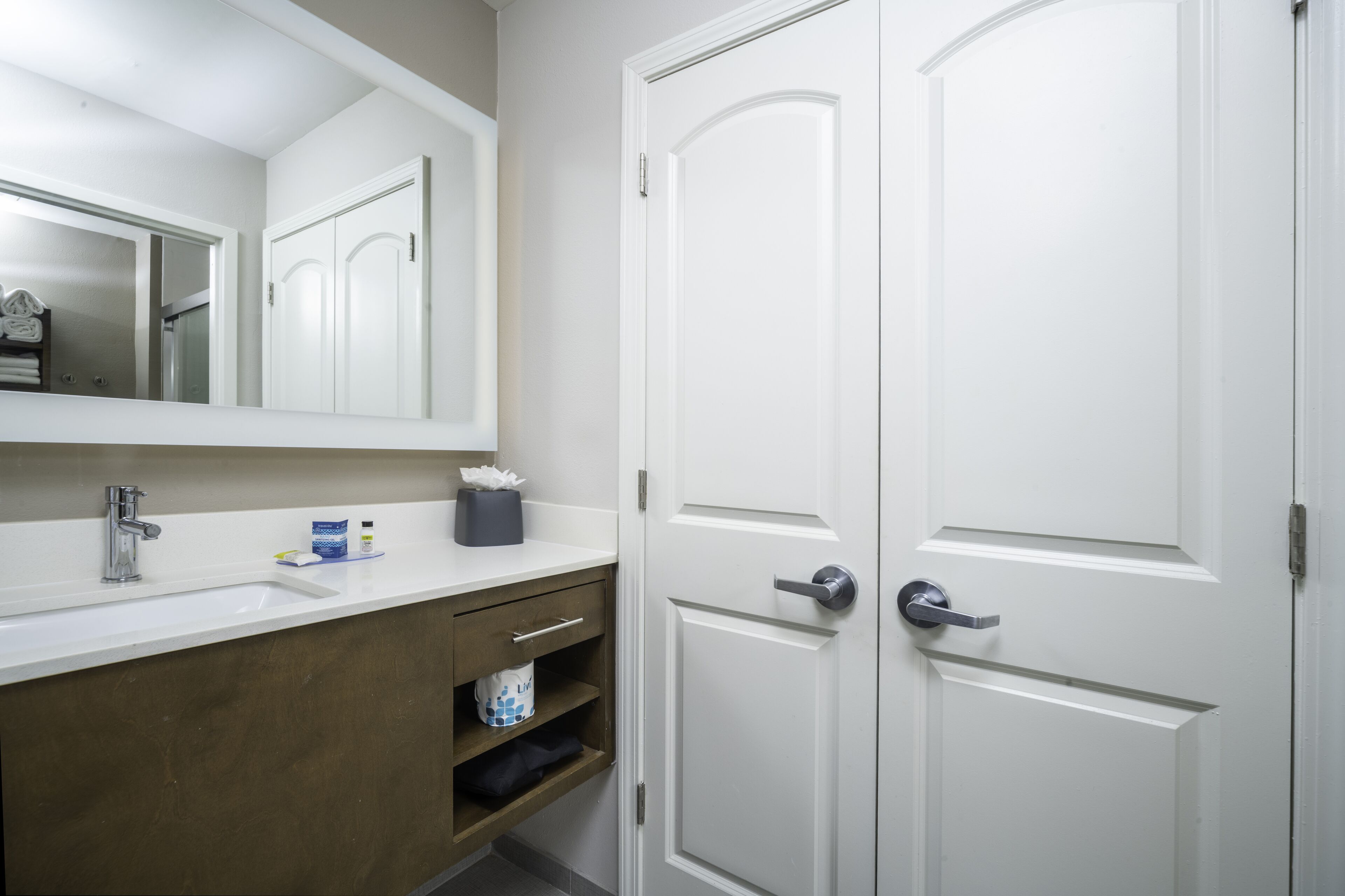 A bathroom with a white sink, mirror, and two white doors.