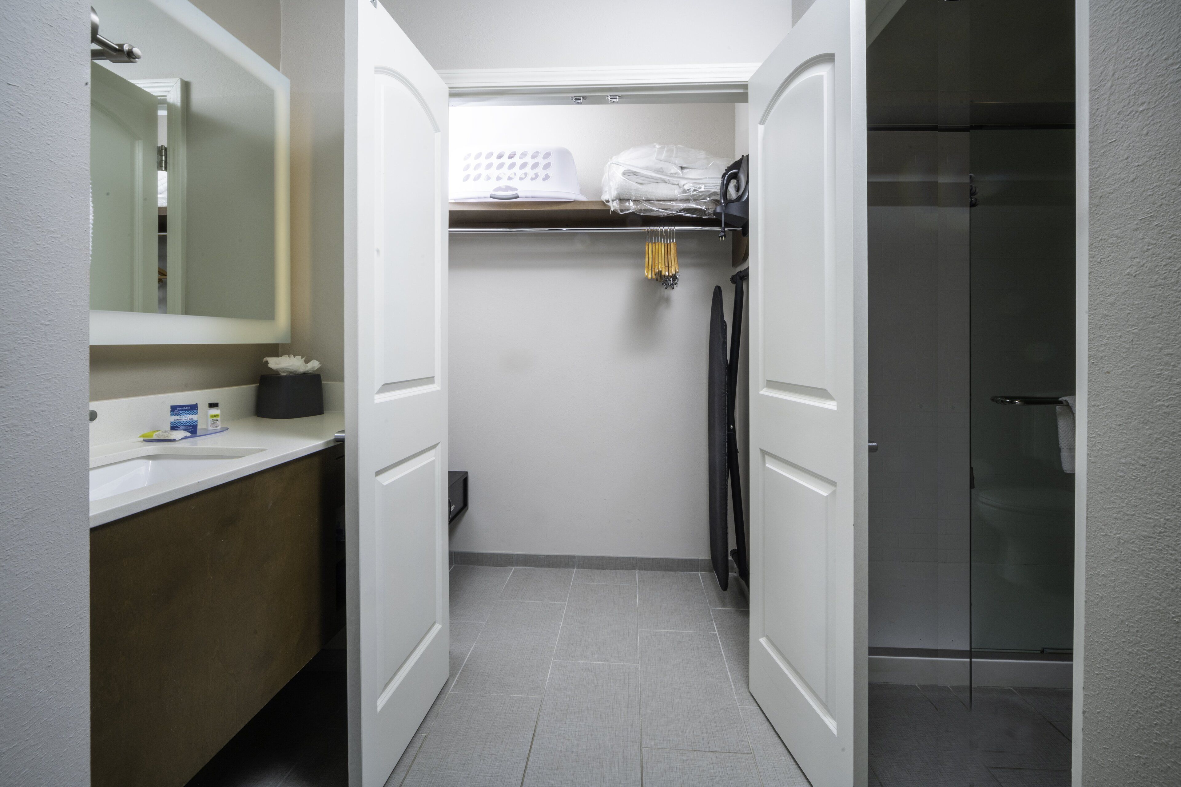 A compact bathroom with a white sink, mirror, and a shower area.