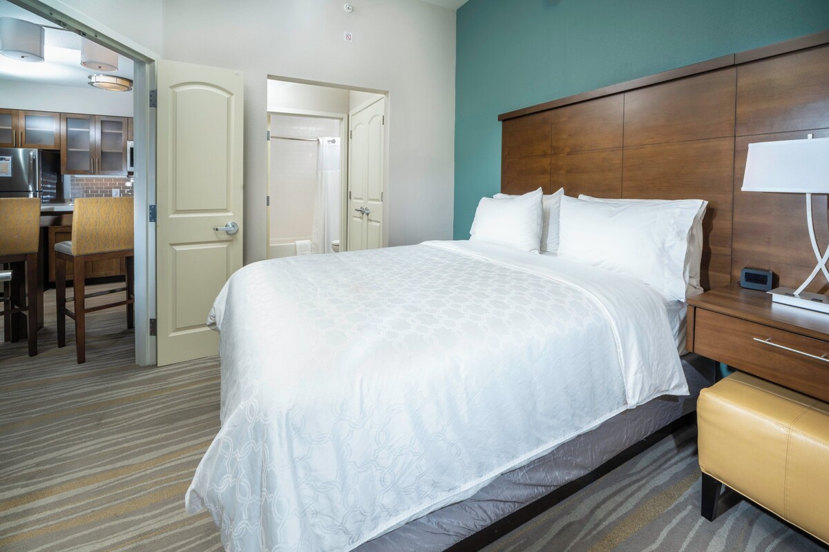 A hotel room with a large bed, a desk, and a chair.