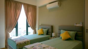 A hotel room with two beds, beige curtains, an air conditioning unit, and a view of the city.