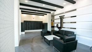 Een moderne lobby met een receptiebalie, zwart-wit zitplaatsen en een behang met een patroon.