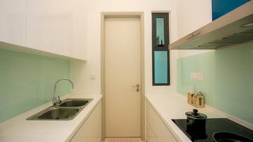 A compact kitchen with two stainless steel sinks, a black stove, and a door with a small window.