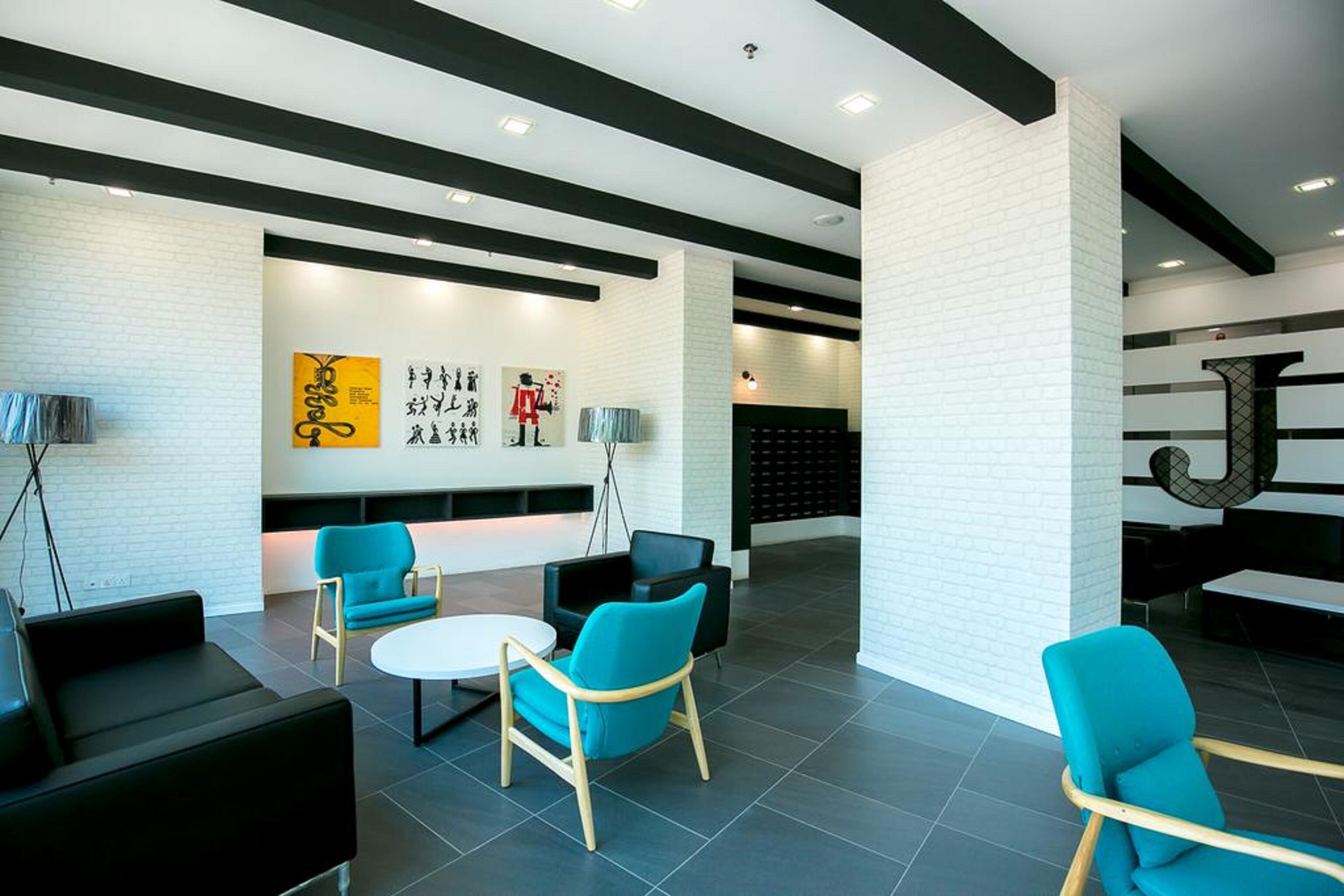 A modern lobby with a white brick wall, black and white furniture, and a large abstract artwork.